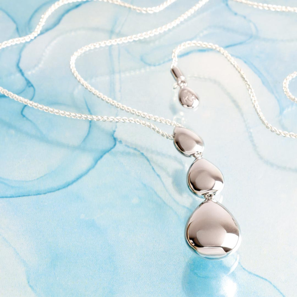 Silver necklace with a pendant on a light blue textured background