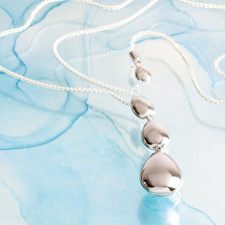 Silver necklace with a pendant on a light blue textured background