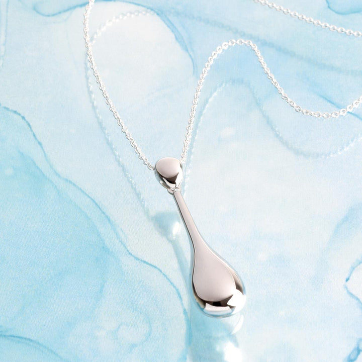 Silver teardrop pendant necklace on a light blue marbled background
