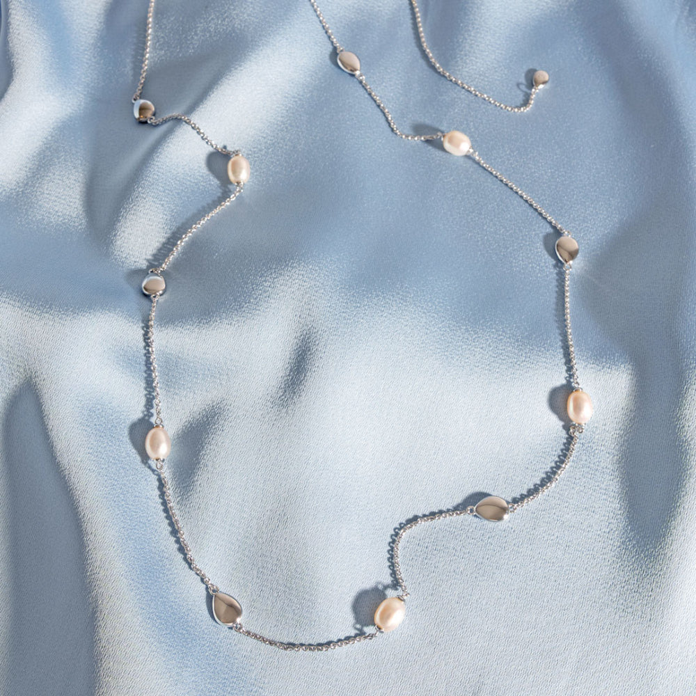 Necklace with pear-shaped beads on a light blue fabric background