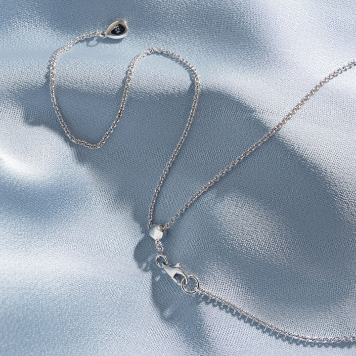 Silver necklace with a clasp on a light blue fabric background