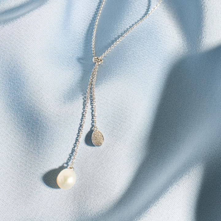 Pearl necklace on a light blue fabric background