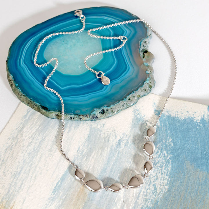 Silver necklace with pebble-like pendants on a blue agate stone