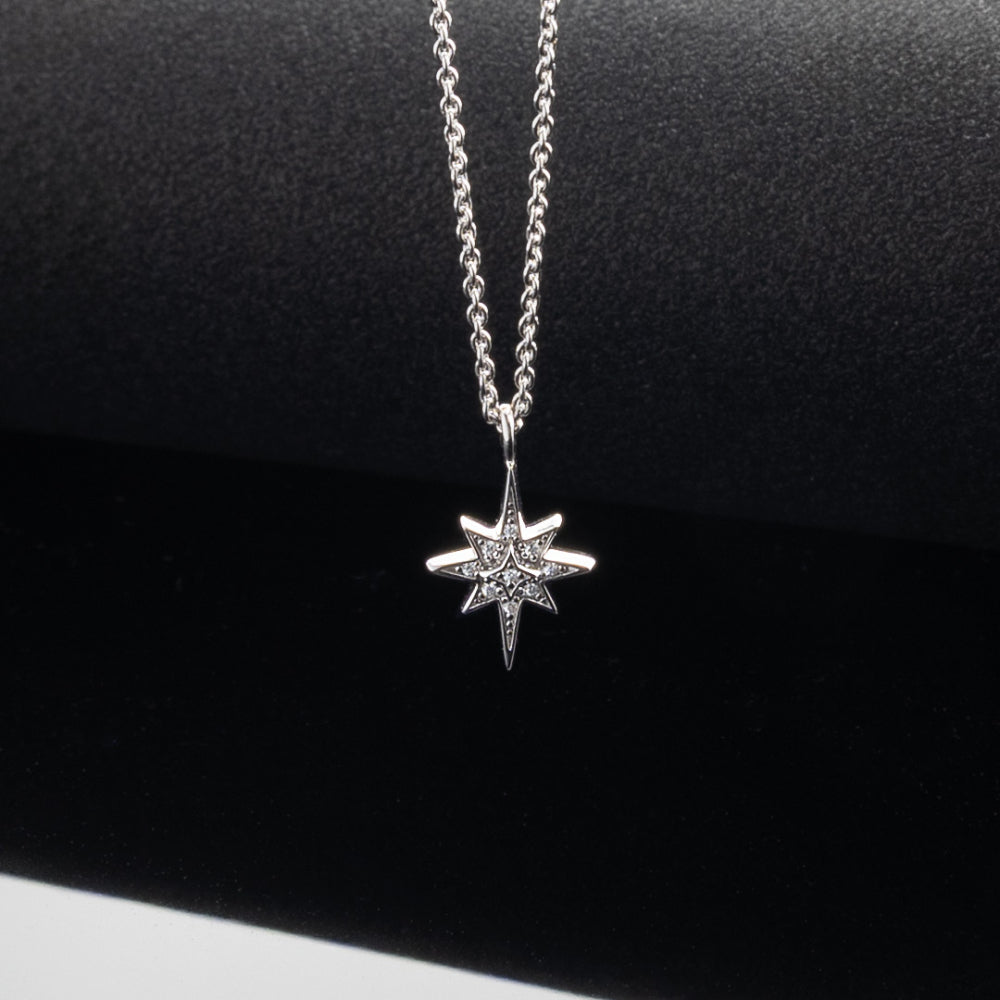 Silver star-shaped pendant necklace on a black background