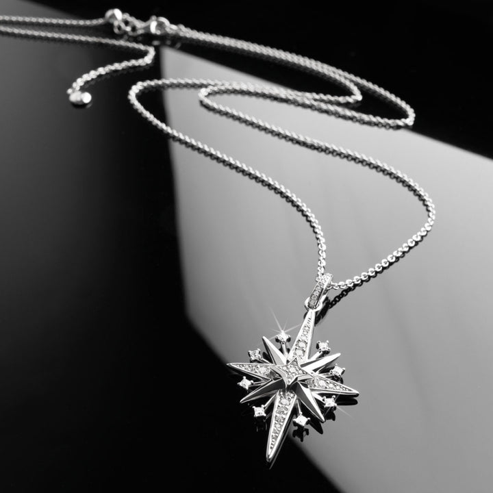 Silver star-shaped pendant necklace on a dark background