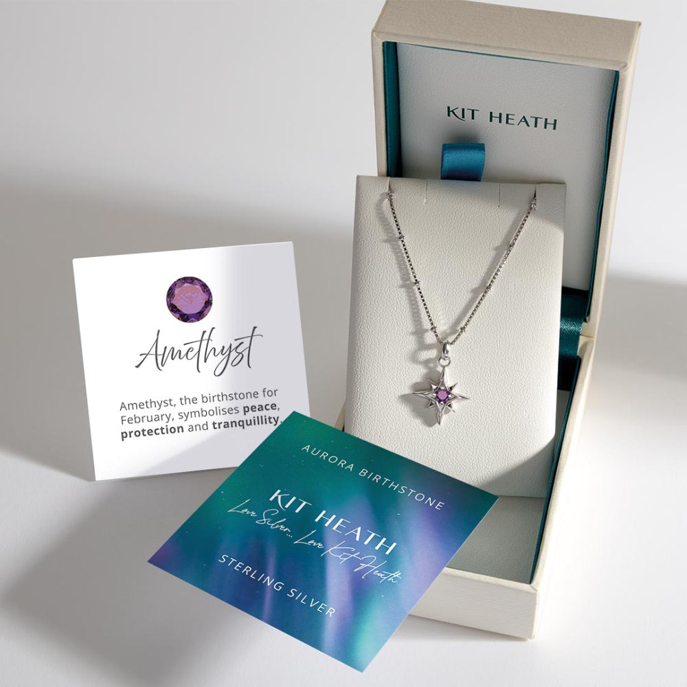 Silver necklace with a purple gemstone in a Kit Heath box, accompanied by information cards.