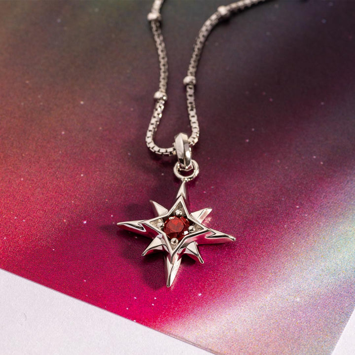 Silver star-shaped pendant with a red gemstone on a chain against a colorful gradient background