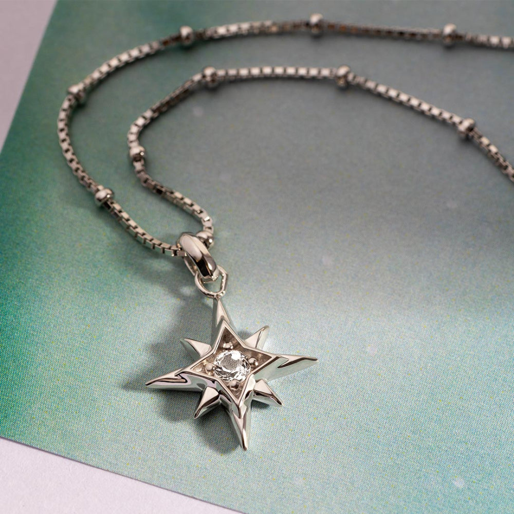 Silver star-shaped pendant necklace on a textured green surface