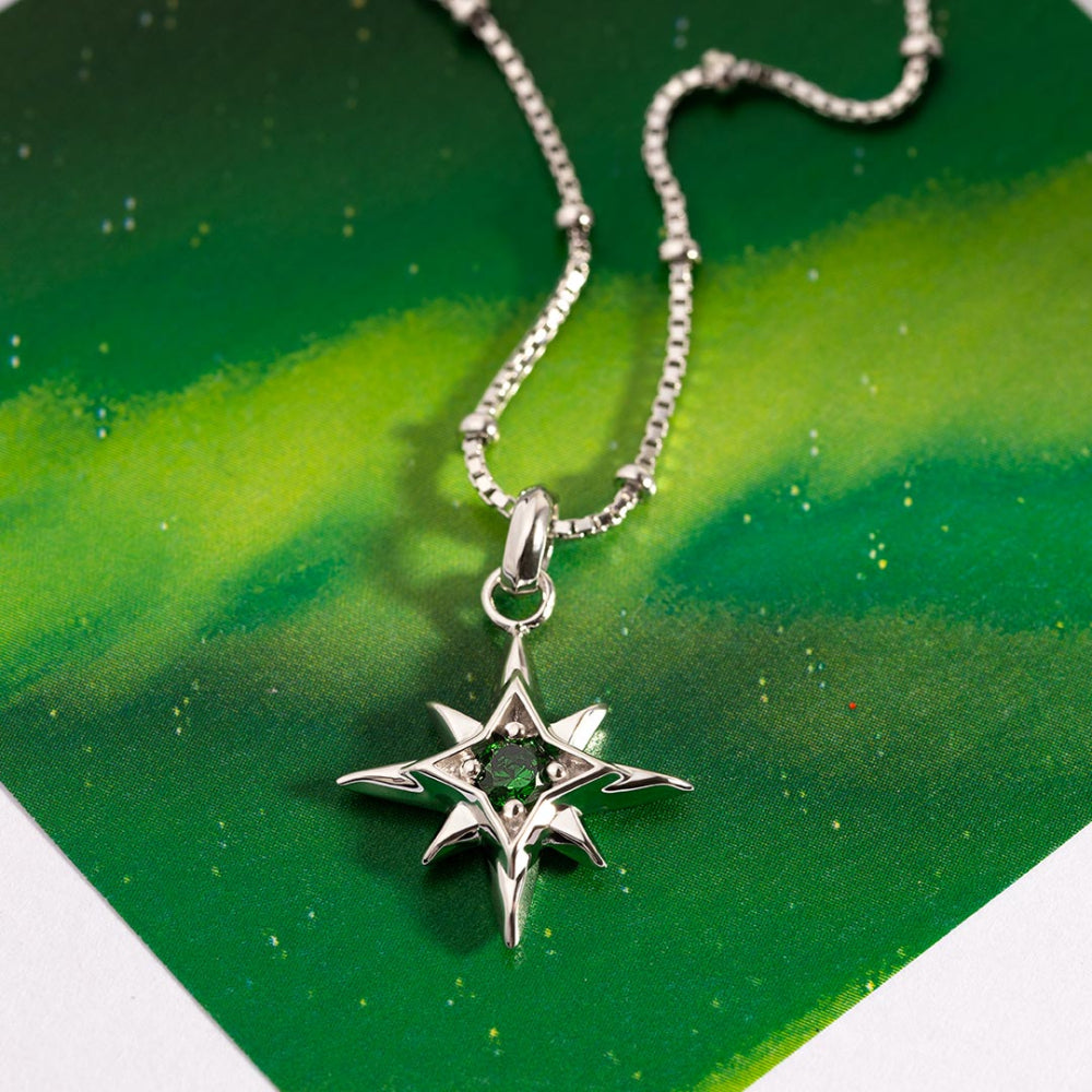Silver star-shaped pendant with a green gemstone on a green background