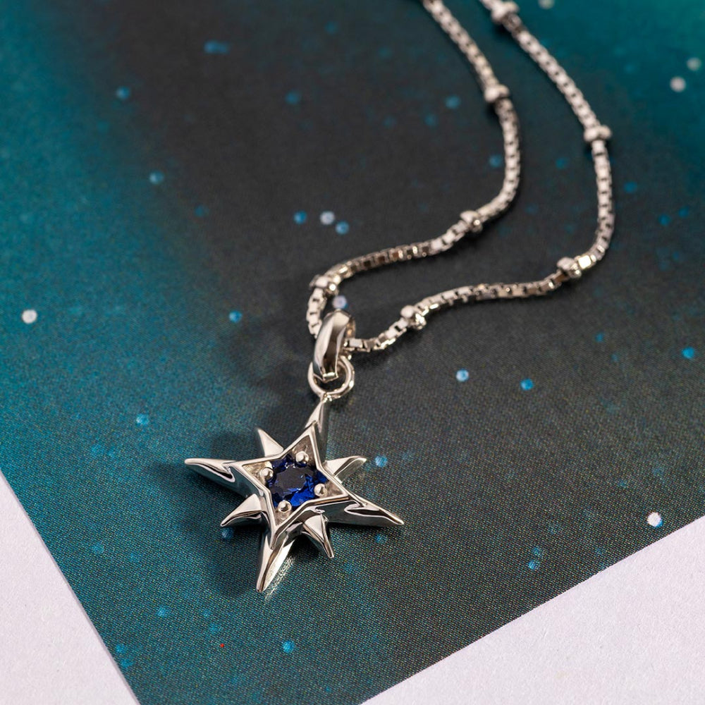 Star-shaped pendant necklace with blue gemstone on a dark textured background