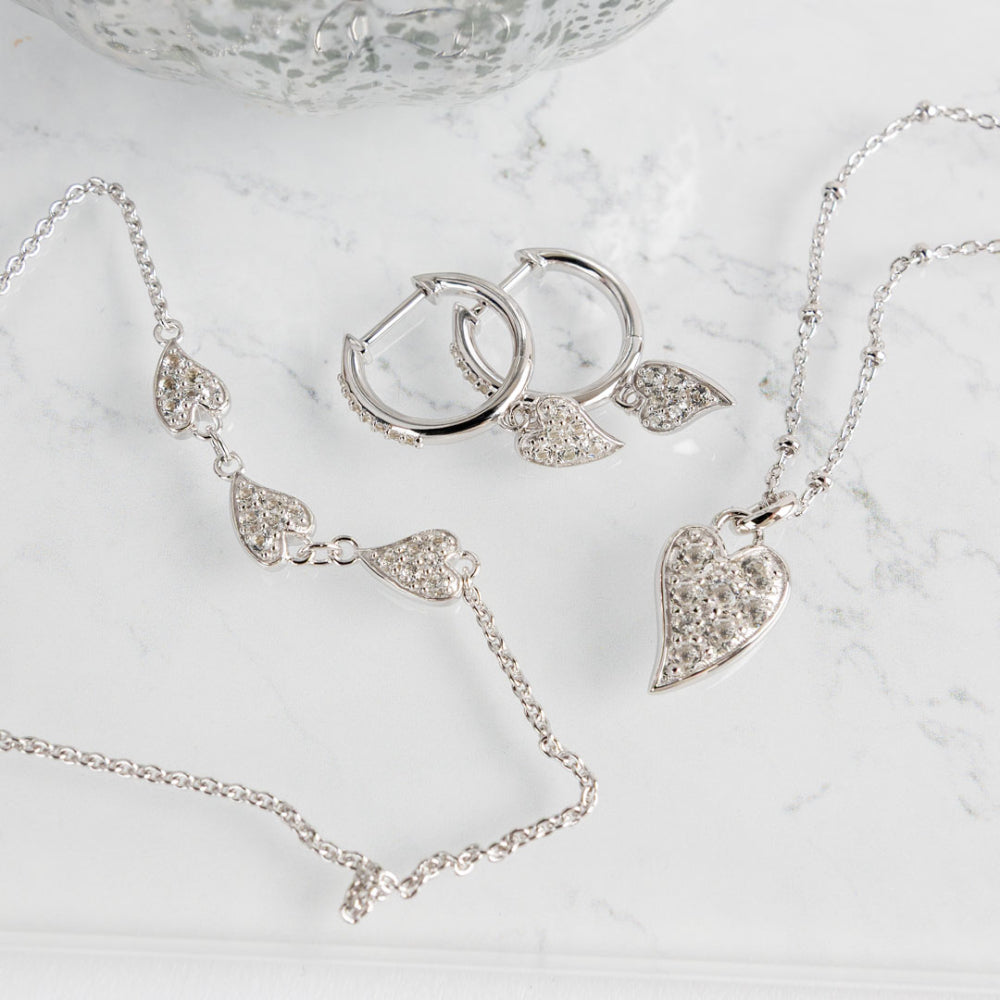 Silver jewelry set including necklace, earrings, and bracelet on a marble surface