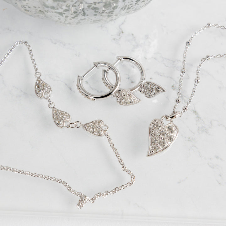 Silver jewelry set including necklace, earrings, and bracelet on a marble surface