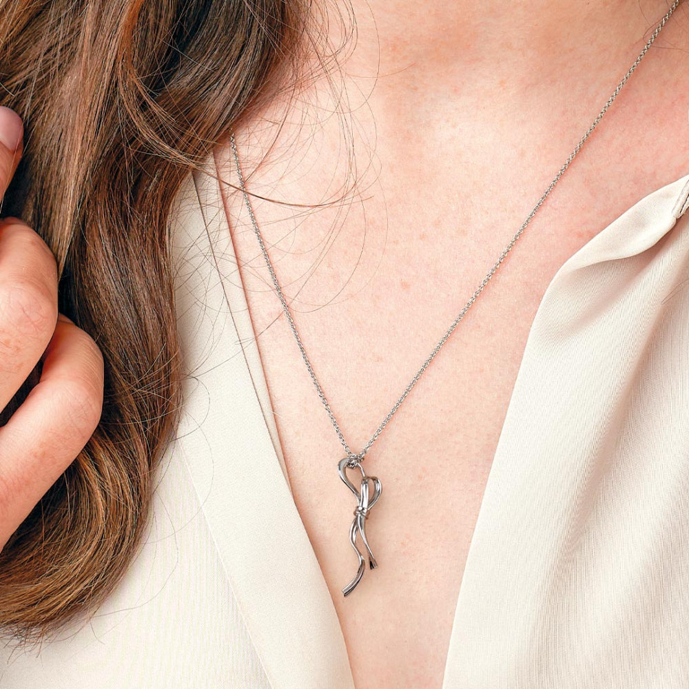 Silver necklace with a unique pendant worn by a person against a neutral background