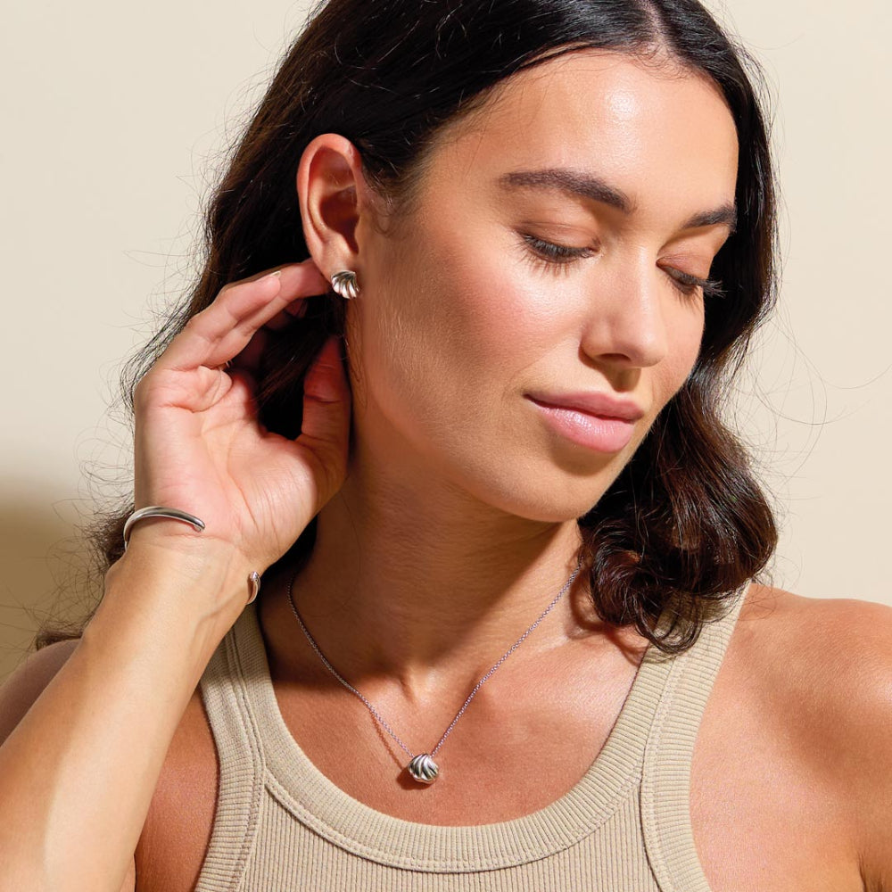 Woman wearing a necklace and earrings, looking down.