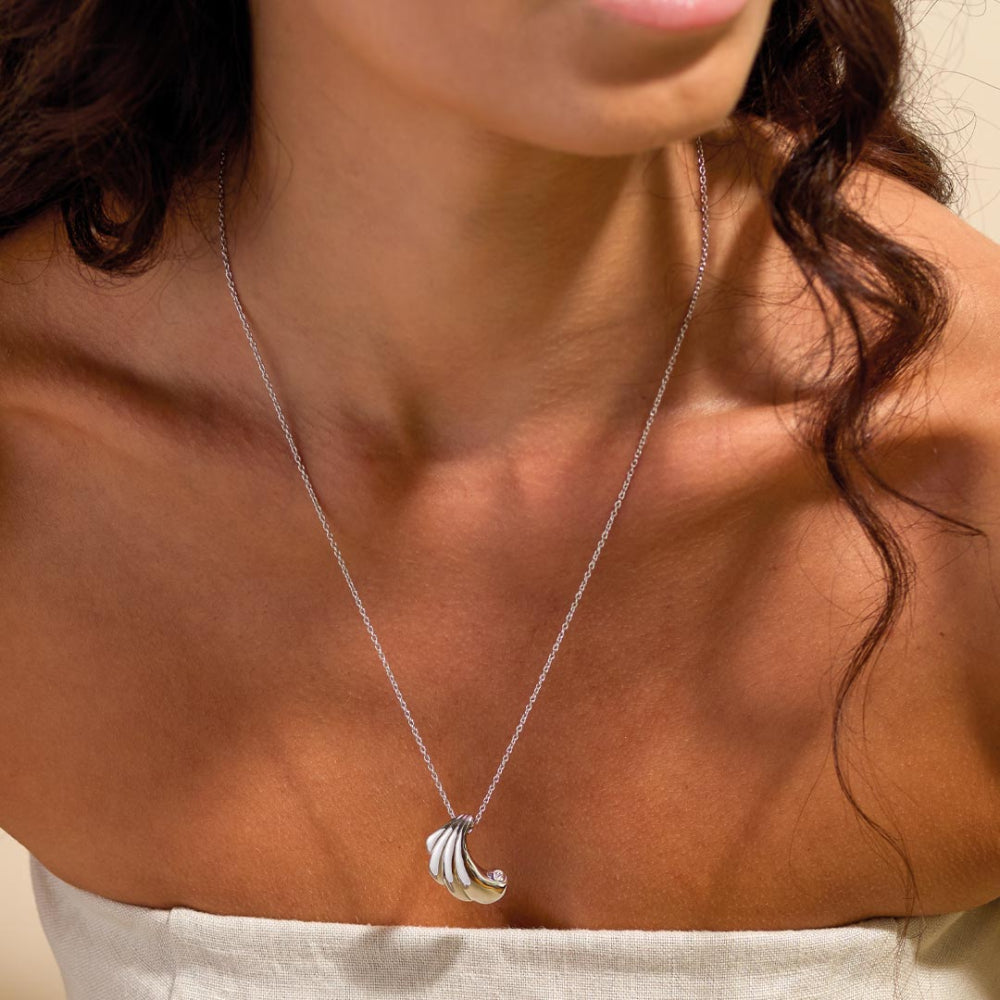 Silver necklace with a leaf pendant worn by a person
