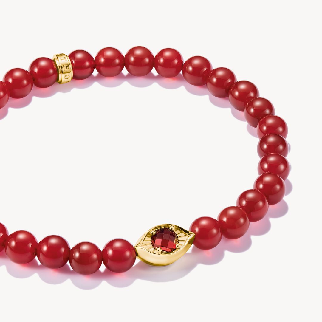 Red beaded bracelet with gold accents and red gemstones on a white background