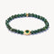 Green beaded bracelet with gold accents on a white background