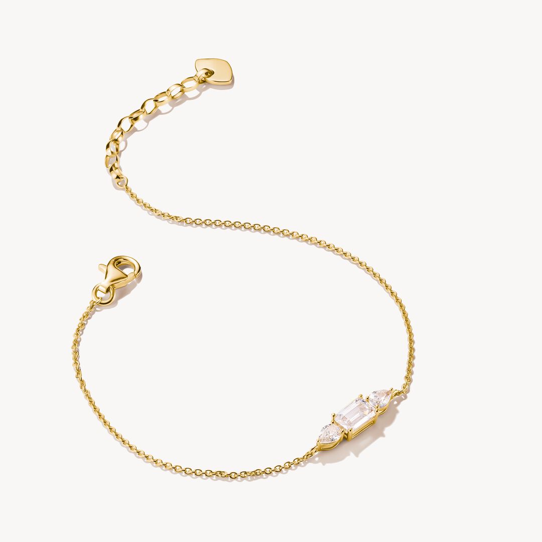 Gold bracelet with heart clasp and clear gemstones on a white background