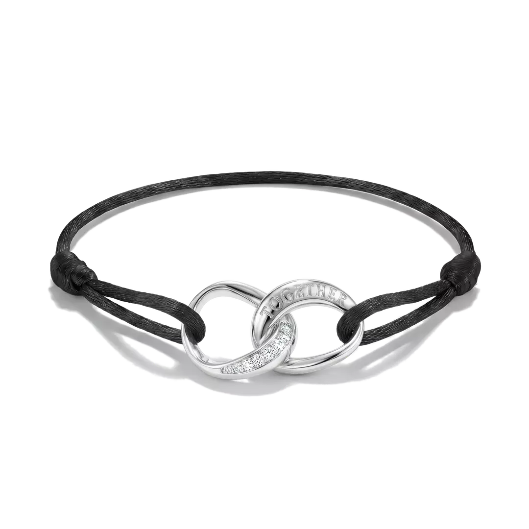 A black cord bracelet with a polished silver infinity-style centerpiece featuring a curved section engraved with the word 'LOVE' and a small line of clear stones, shown on a white background.
