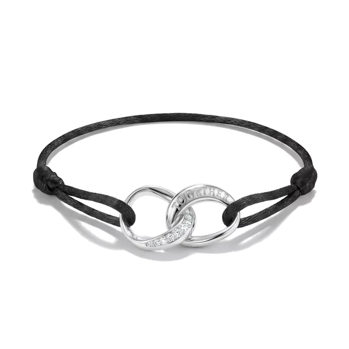 A black cord bracelet with a polished silver infinity-style centerpiece featuring a curved section engraved with the word 'LOVE' and a small line of clear stones, shown on a white background.