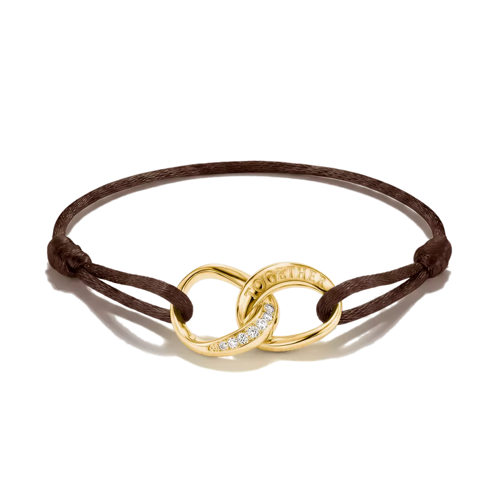 A brown cord bracelet featuring an interlocking gold infinity-style charm with a pavé diamond accent and the brand name 'Chap-Guillaume' engraved on one loop, shown on a white background.