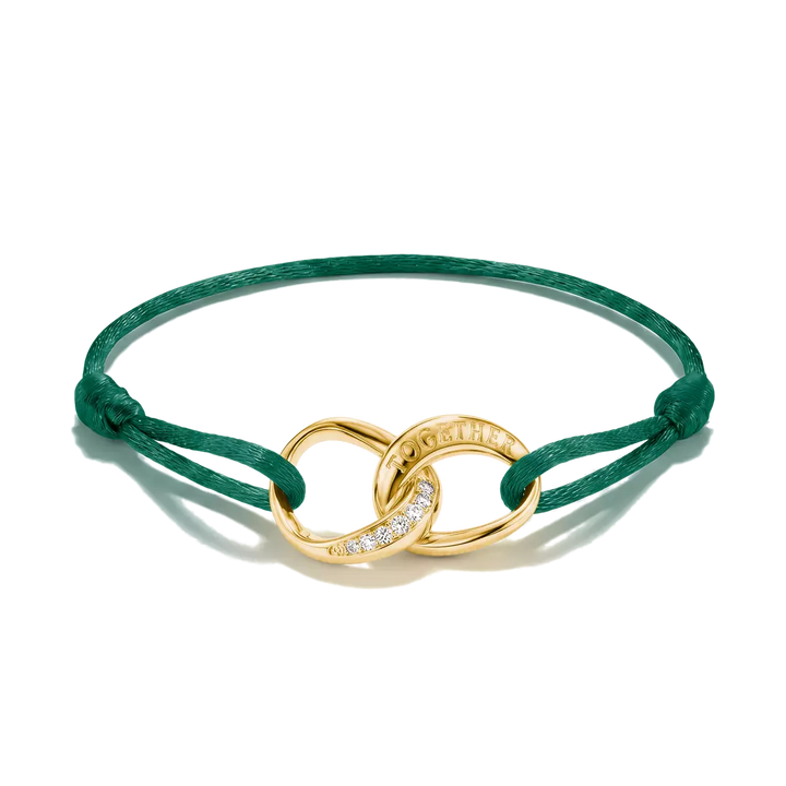 A green cord bracelet with a gold infinity-style link centerpiece featuring a row of small clear stones and the brand name 'Chanel' engraved on one side, shown on a white background.