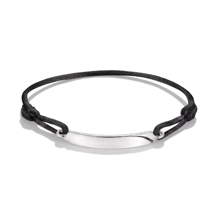 A minimalist black cord bracelet with a polished silver-tone oval plate in the center, displayed on a clean white background.