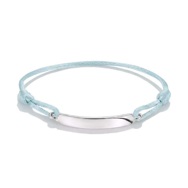 A delicate pink cord bracelet with a polished silver-tone oval plate in the center, displayed on a clean white background.