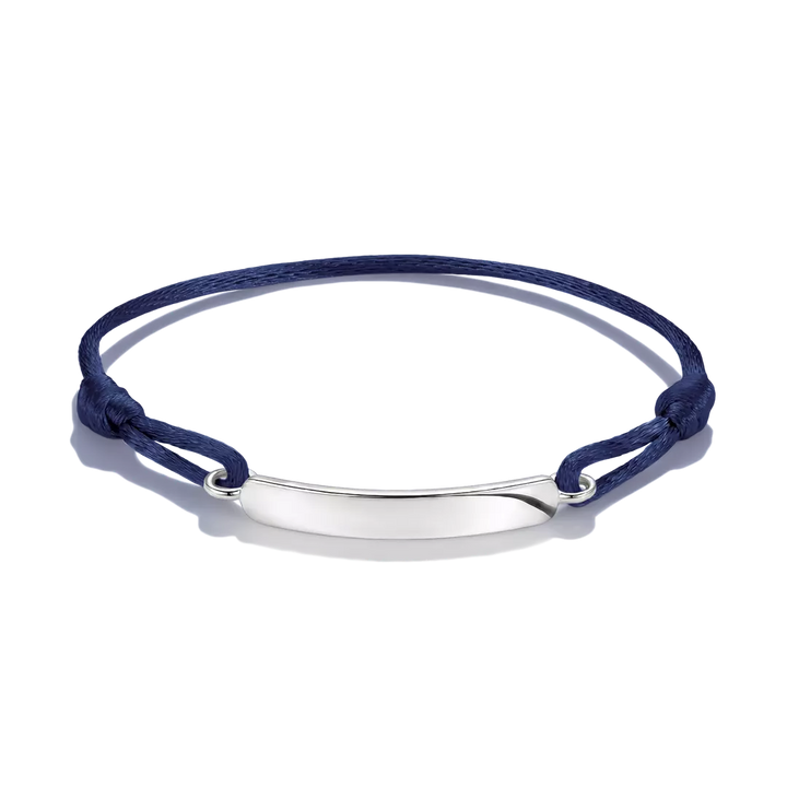A navy blue cord bracelet with a polished silver-tone oval ID plate, shown on a clean white background.