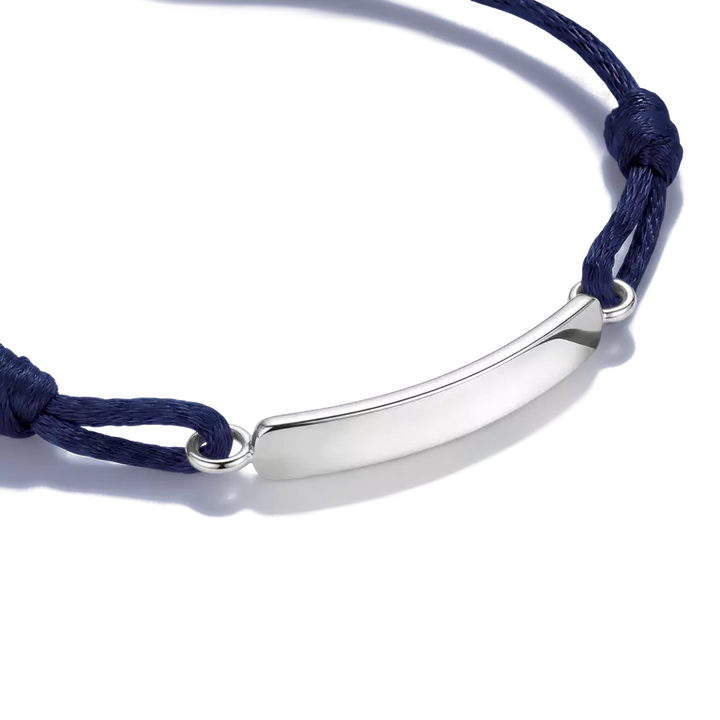 A silver curved bar nameplate bracelet on a navy blue cord, shown on a clean white background.