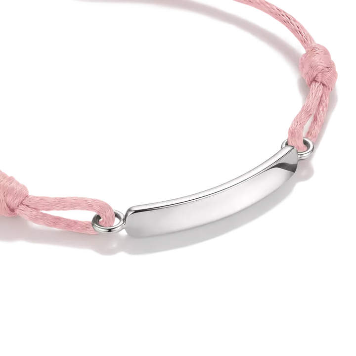 A delicate pink cord bracelet with a polished silver-tone oval plate in the center, displayed on a clean white background.