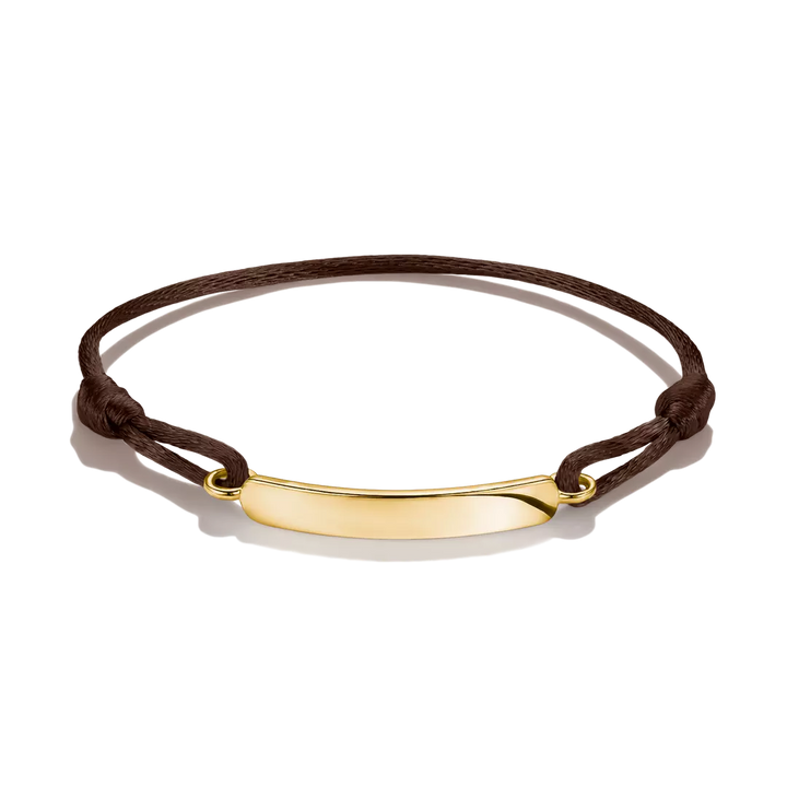 A dark brown cord bracelet with a polished gold-tone curved bar pendant, displayed on a clean white background.