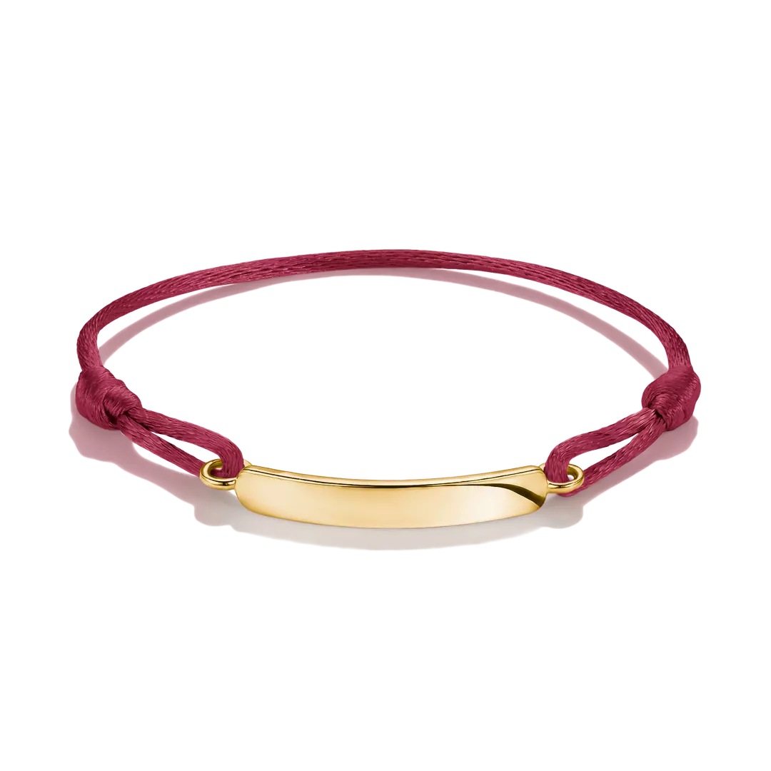 A magenta pink cord bracelet with a polished gold ID plate, displayed on a clean white background.
