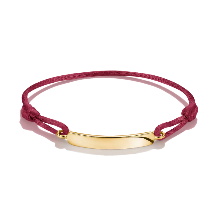 A magenta pink cord bracelet with a polished gold ID plate, displayed on a clean white background.