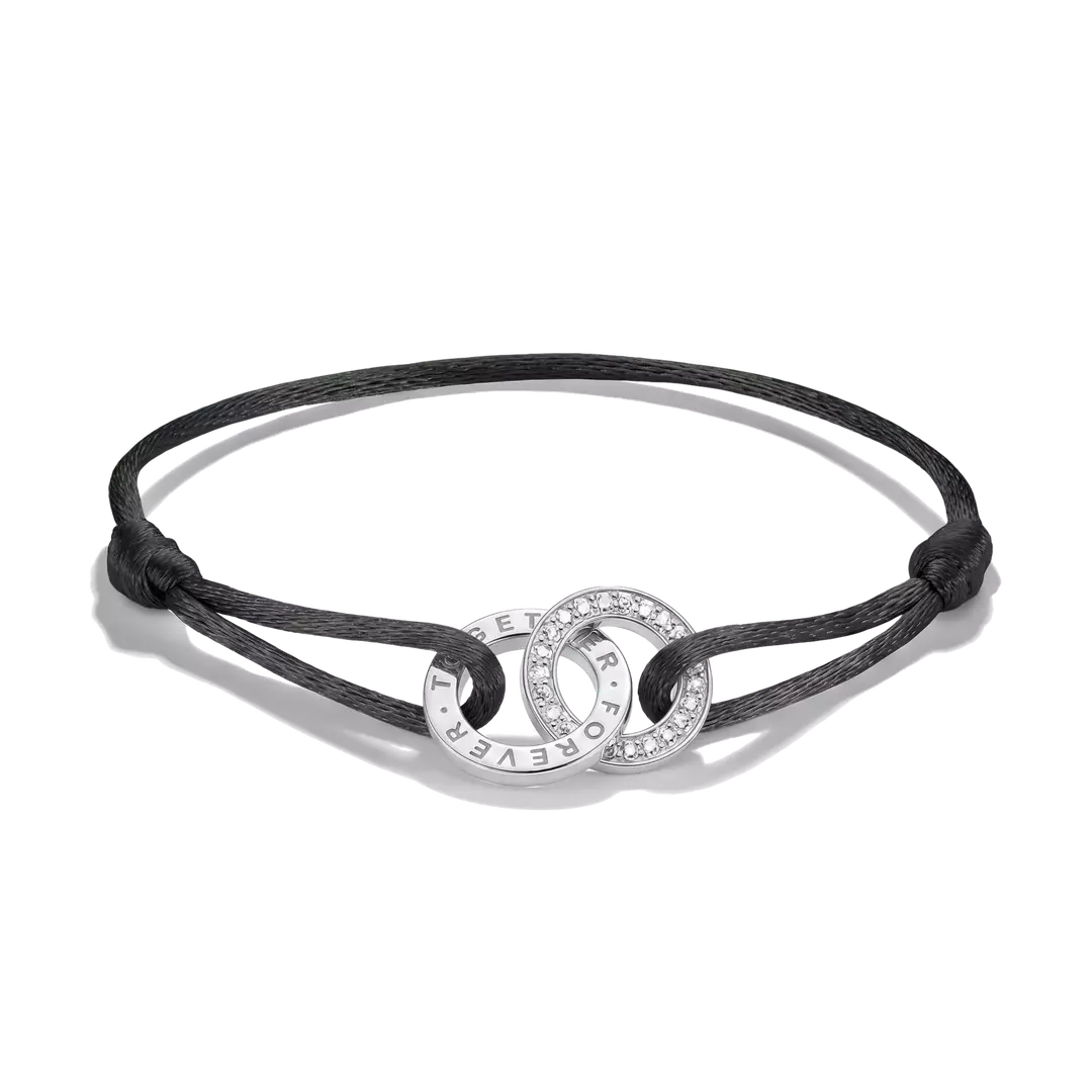 A black cord bracelet with two interlocking silver rings, one of which is paved with small clear stones and features the text 'I WILL NEVER FORGET YOU' engraved on the other, shown on a white background.