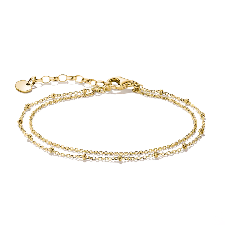 A delicate double-strand gold chain bracelet with small bead accents, a lobster clasp, and an adjustable extender chain with a round tag, shown on a plain white background.