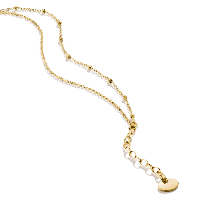 A gold chain necklace featuring a delicate beaded section, a short chain segment, and a small flat oval pendant, displayed on a clean white background.
