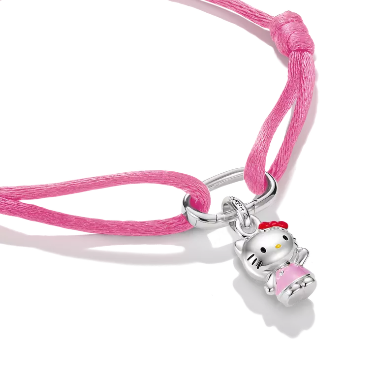 A pink cord bracelet featuring a silver Hello Kitty charm holding a pink book, shown on a clean white background.