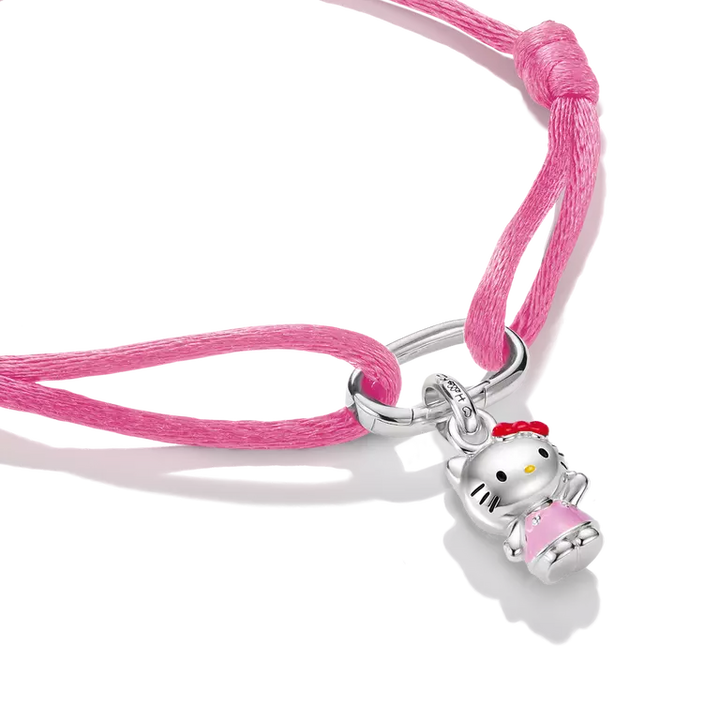 A pink cord bracelet featuring a silver Hello Kitty charm holding a pink book, shown on a clean white background.