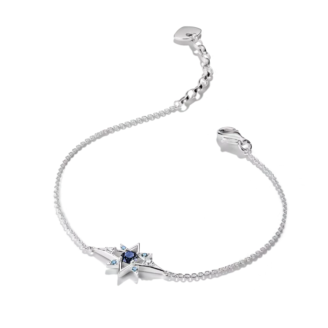 A delicate silver chain bracelet featuring a central starburst charm with a dark blue center stone and small light blue accent stones, displayed on a clean white background.