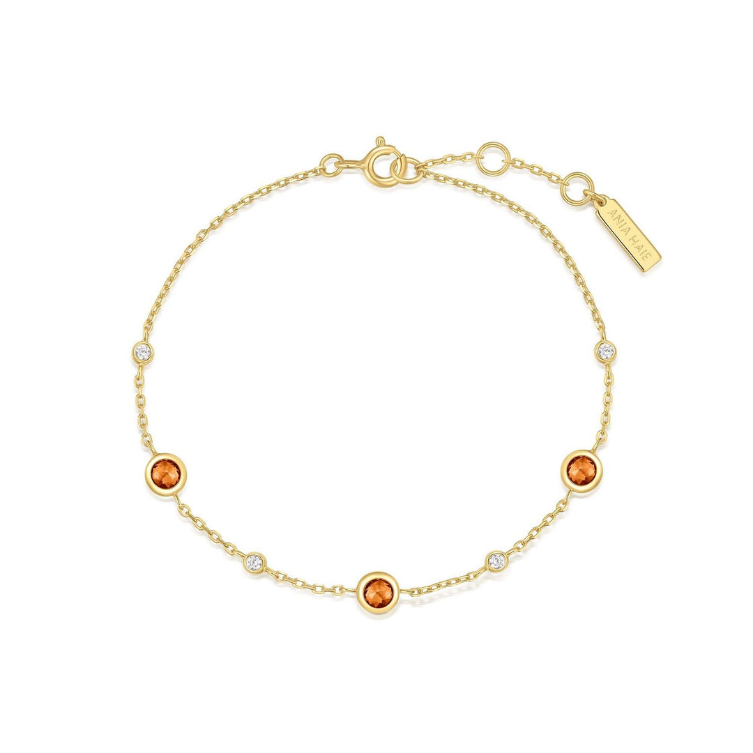 Gold bracelet with orange gemstones on a white background