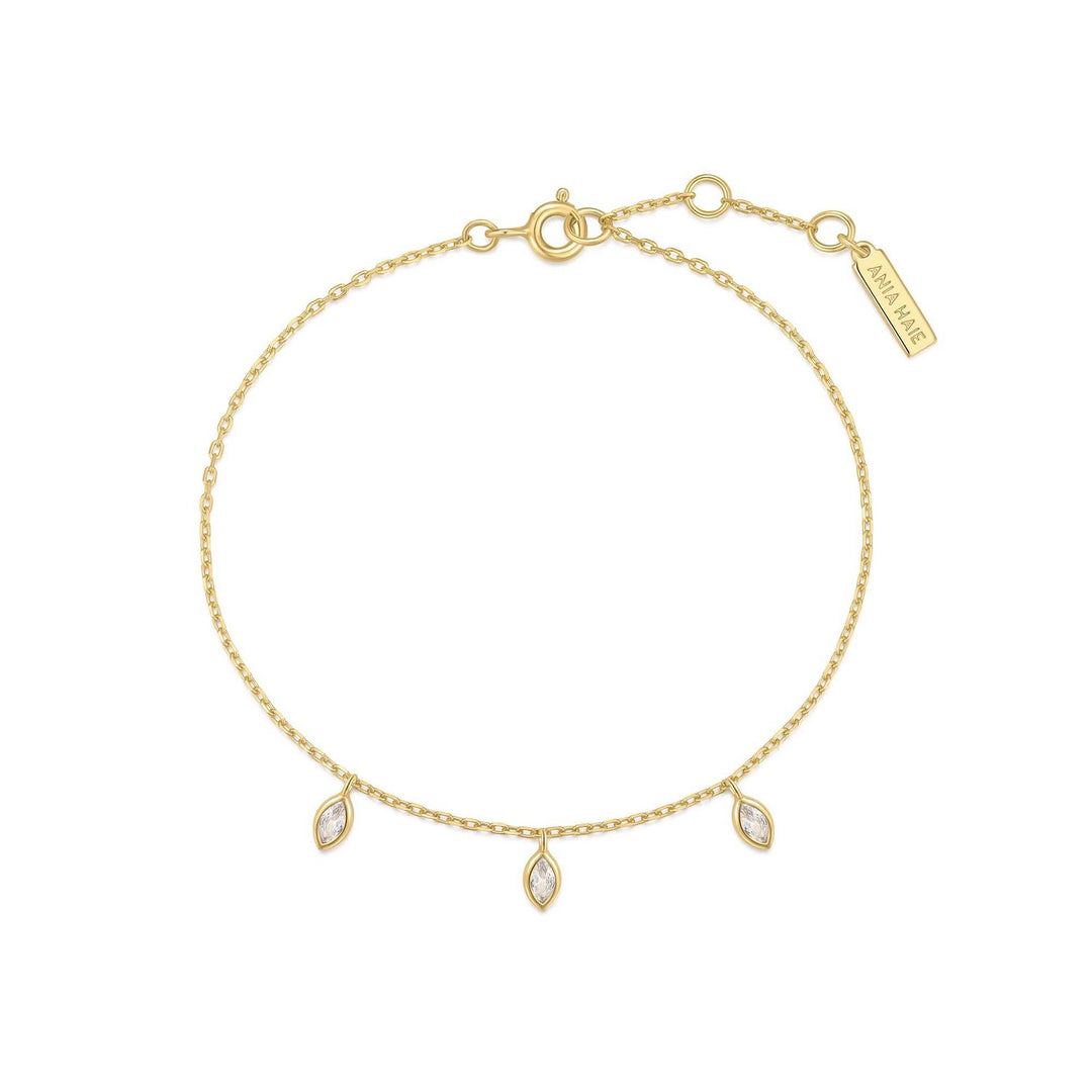Gold bracelet with three small diamond-like stones on a white background