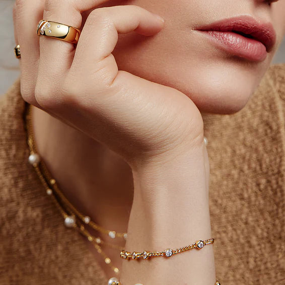 Close-up of a hand wearing gold jewelry with a blurred background