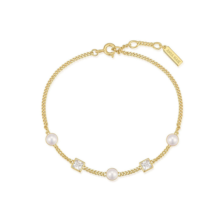Gold bracelet with pearls and crystals on a white background