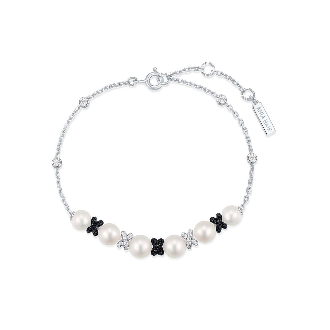 Pearl bracelet with black flower-shaped charms on a white background