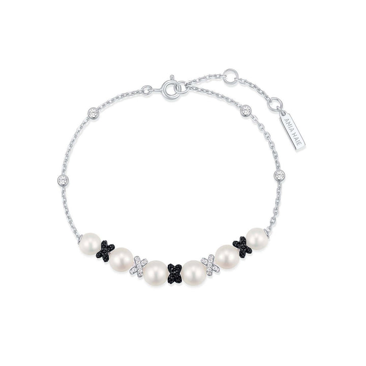 Pearl bracelet with black flower-shaped charms on a white background