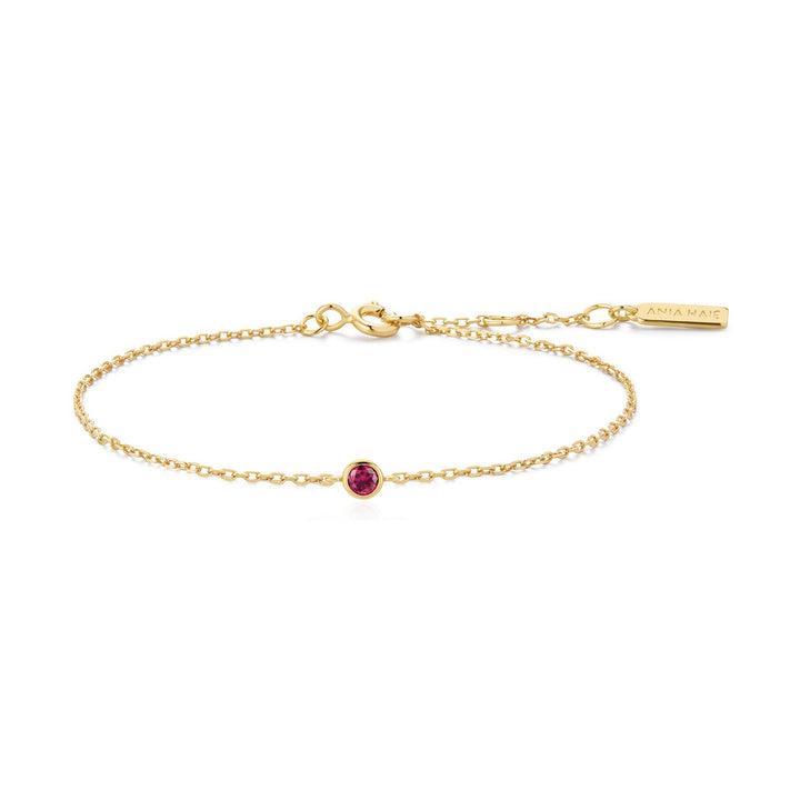 Gold bracelet with a red gemstone on a white background