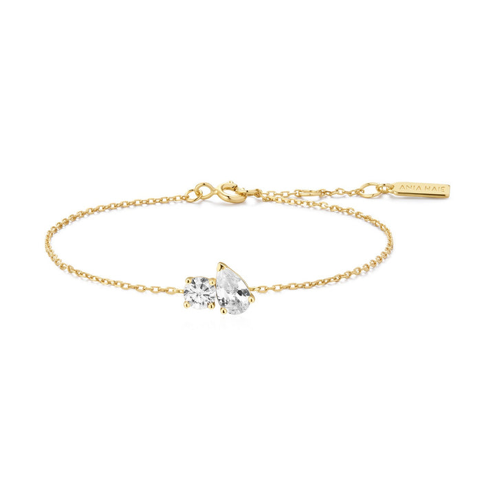 Gold bracelet with a clear heart-shaped gemstone on a white background