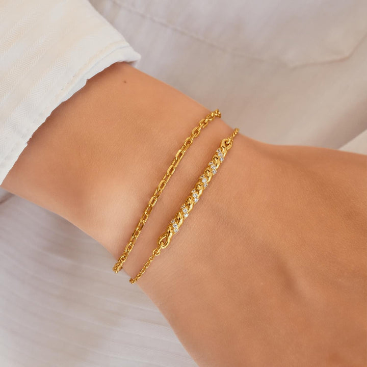 Gold chain bracelet on a wrist with a neutral background