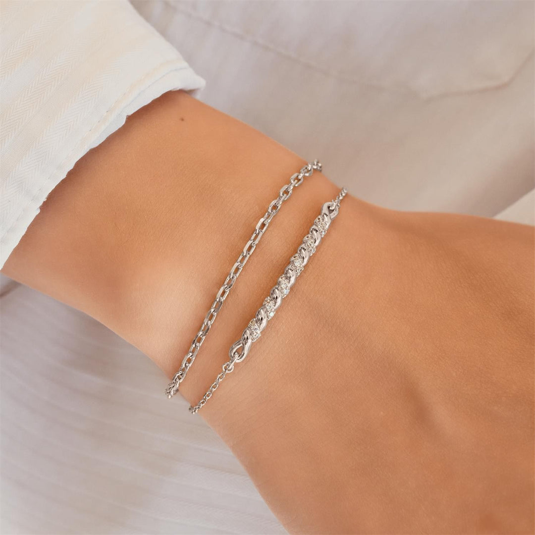 Silver chain bracelet on a wrist with a neutral background